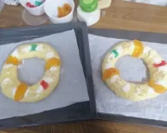 Step <p>Para formar a los dos roscos, introduzca los dedos en el centro y abra la masa de modo que el agujero central sea bastante grande, coloque cada rosco en las bandejas de horno preparadas</p> illustration